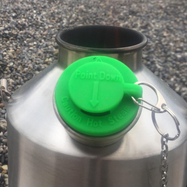 A stainless steel kettle with a green lid suitable for emergency food storage.