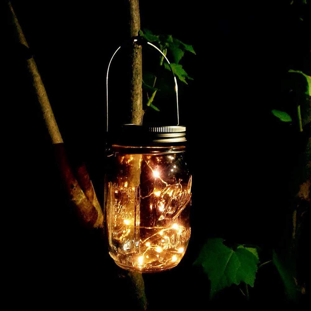 A mason jar with lights hanging from a tree.