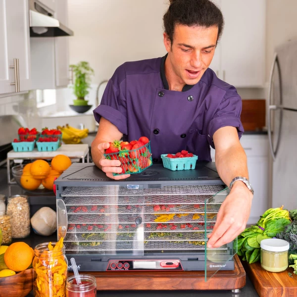 A man preparing food in a kitchen with a food dehydrator.