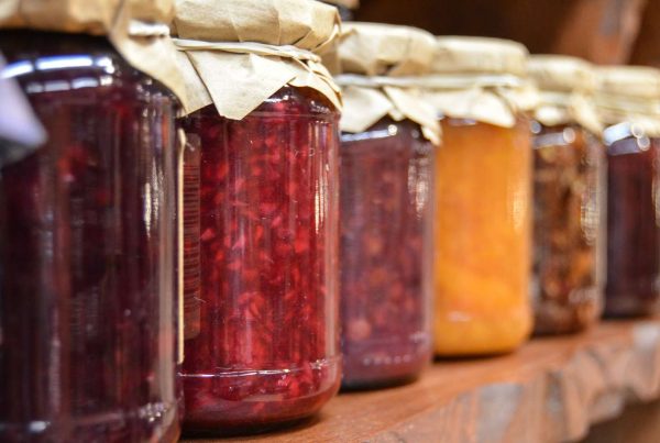 Jars of jam, ideal for emergency food storage, are lined up on a shelf.
