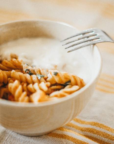 A bowl of pasta for emergency food storage with yogurt and a fork.