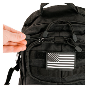 A person is holding a Black Tactical Outdoor Backpack with an American flag on it.