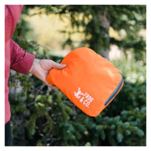 A person holding a orange bag in front of a tree.
