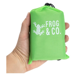 A person holding a green bag with the Frog & Co. logo on it and a Pocket Blanket inside.