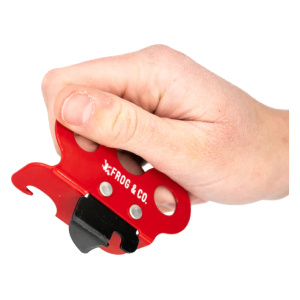 A hand holding a red tool with a red handle, the Emergency Can Opener by Frog & Co.