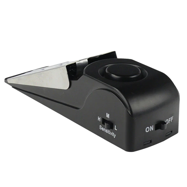 A black device with a button on it that is a Door Stop Alarm, produced by Frog & Co.