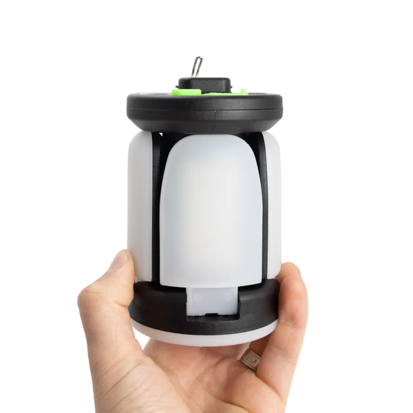 A person holding up a small QuadPod Camping Lantern.